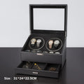 Black leather watch winder box with glass lid, four automatic winders holding watches, and open storage drawer.
