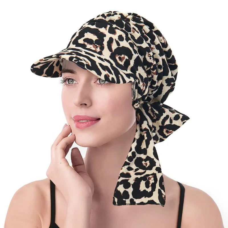 A woman wearing a leopard print headscarf hat with a peak and tie-back detail.