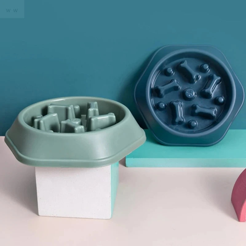 Two hexagonal slow-feeder pet bowls in sage green and dark blue, featuring internal bone-shaped obstacles.