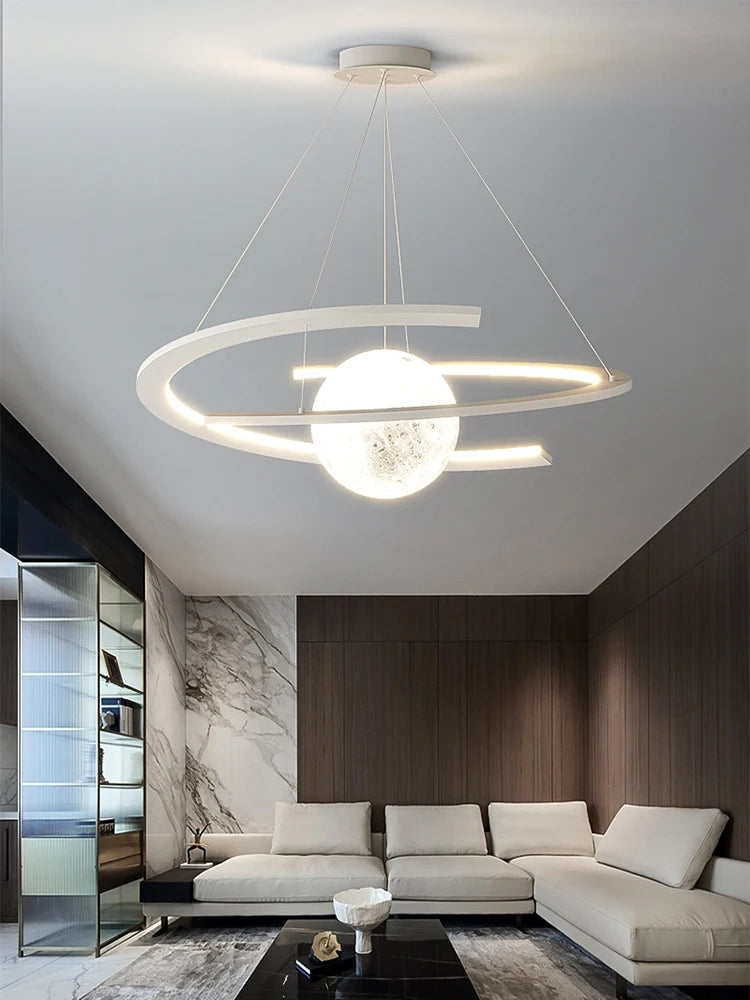 Modern white pendant lamp with a glowing central orb and sleek curved ring, suspended in a contemporary living room.
