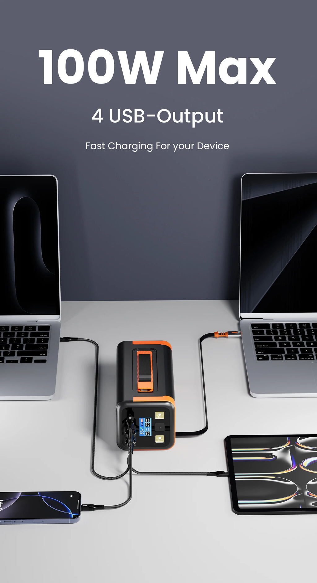 Black and orange portable power bank with four USB outputs charging two laptops, a tablet, and a phone simultaneously.