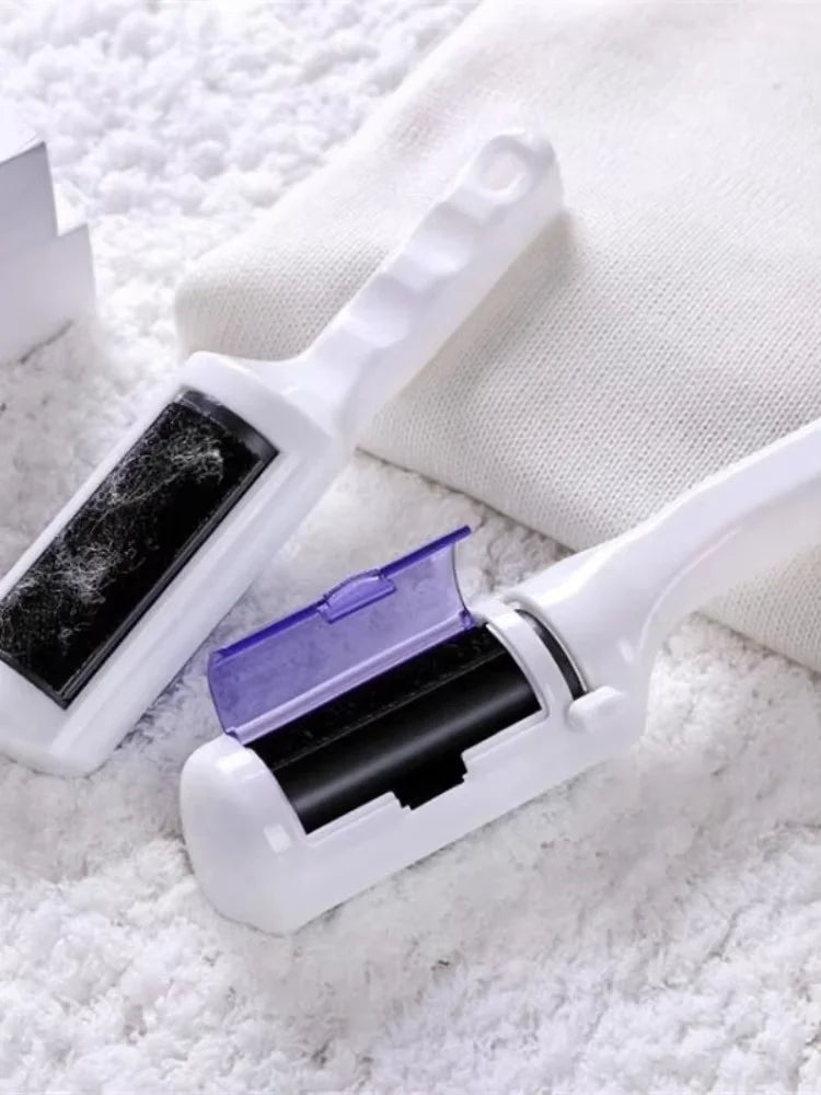 Two white lint removers with black fabric heads and a small purple storage compartment, resting on a white fabric.