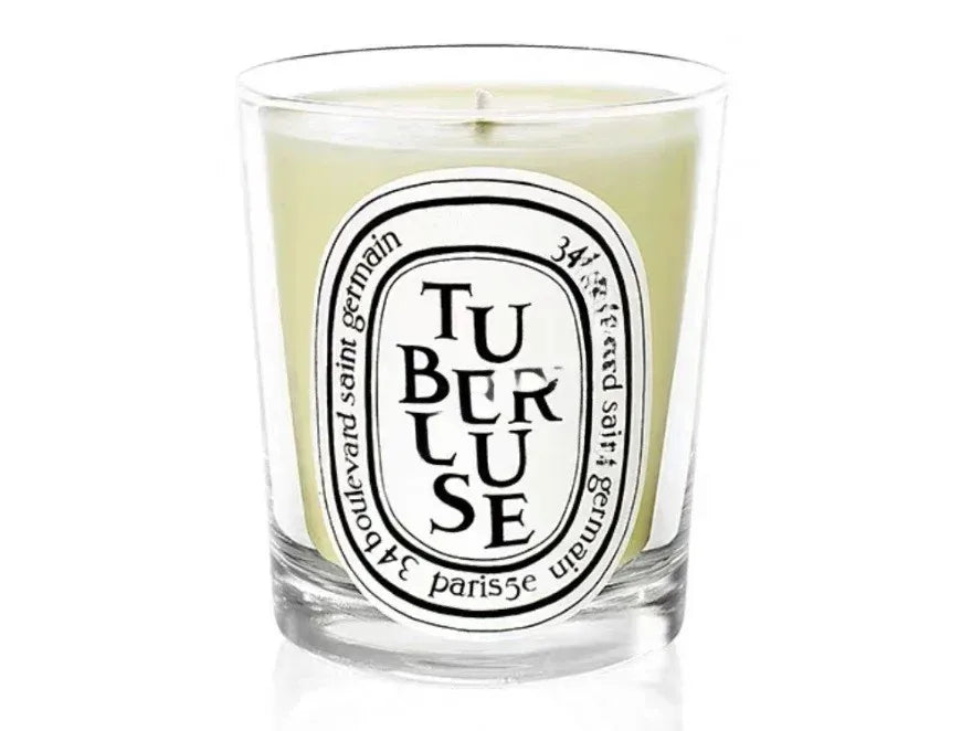 A luxury scented candle in a clear glass jar with a pale yellow wax and a distinctive oval white label.