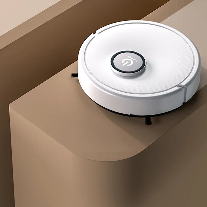 A white robotic vacuum cleaner with a central power button on a tan surface.