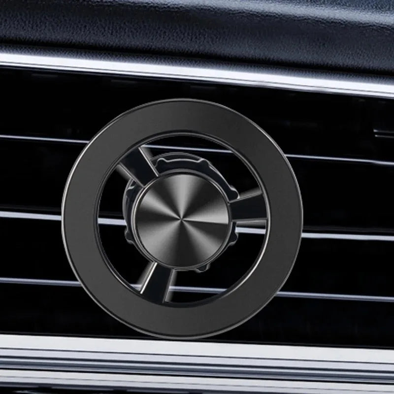 Black circular car air vent fragrance diffuser with a metallic, radial-brushed center design.