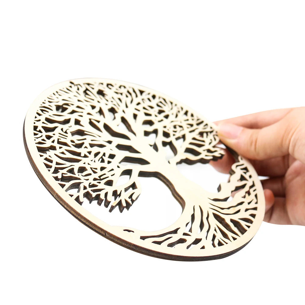Hand holding a round, light wood laser-cut ornament featuring an intricate tree of life design.