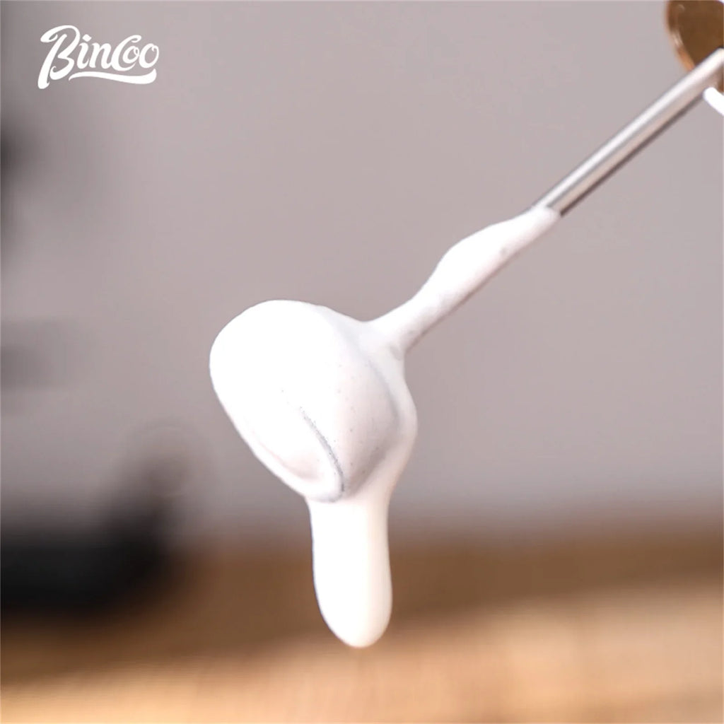 Stainless steel milk frother whisk covered in thick, white, creamy milk foam.