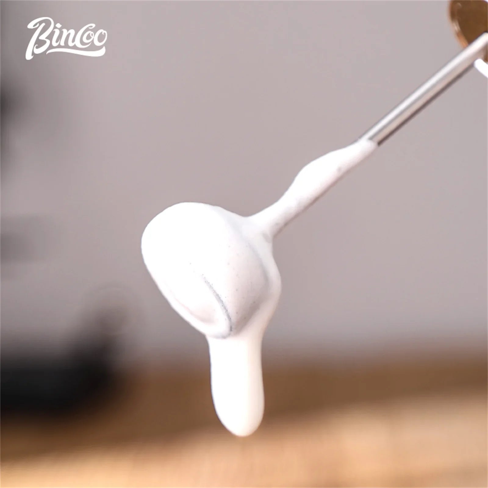 Stainless steel milk frother whisk covered in thick, white, creamy milk foam.