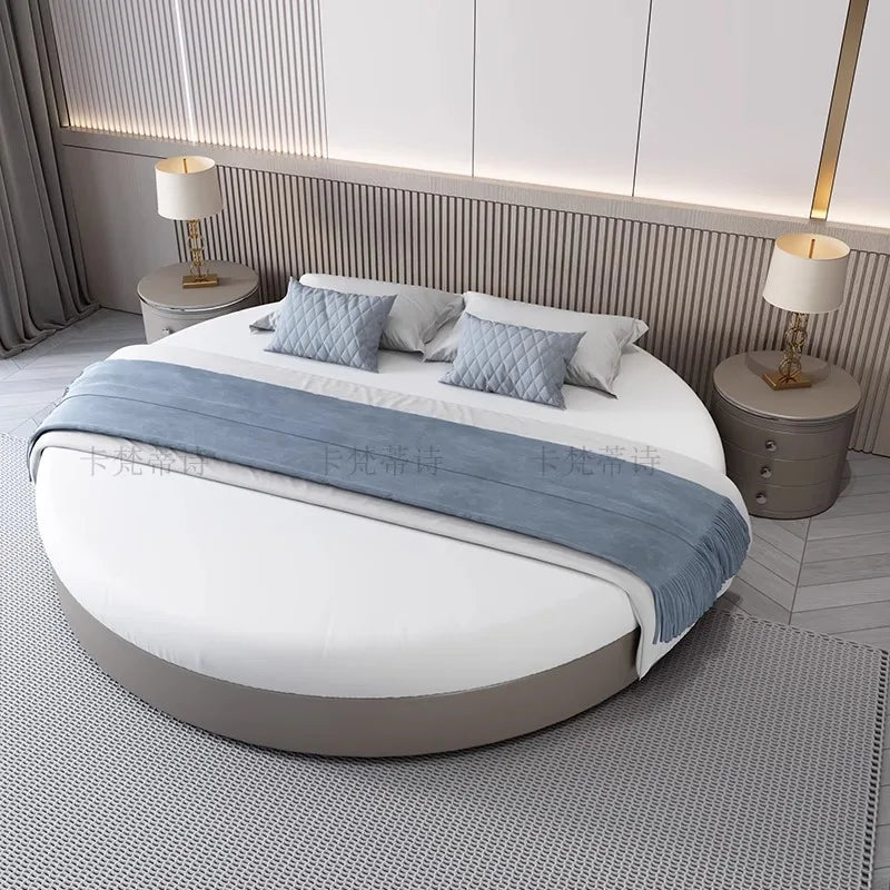 Modern minimalist circular bed frame in grey, styled with white bedding, blue cushions, and a matching grey bed runner.