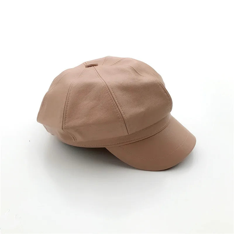 Nude-pink faux leather baker boy cap with a classic paneled design and stiff peak, isolated on a white background.