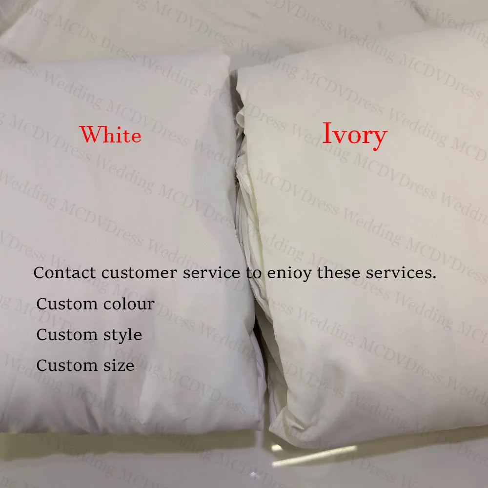 Folded white and ivory satin fabric swatches for custom wedding dresses with text.