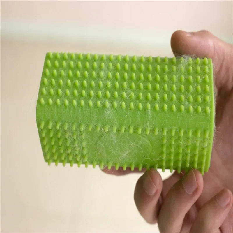 Hand holding a bright green rubber lint brush with small, nubbed bristles covered in collected pet hair.