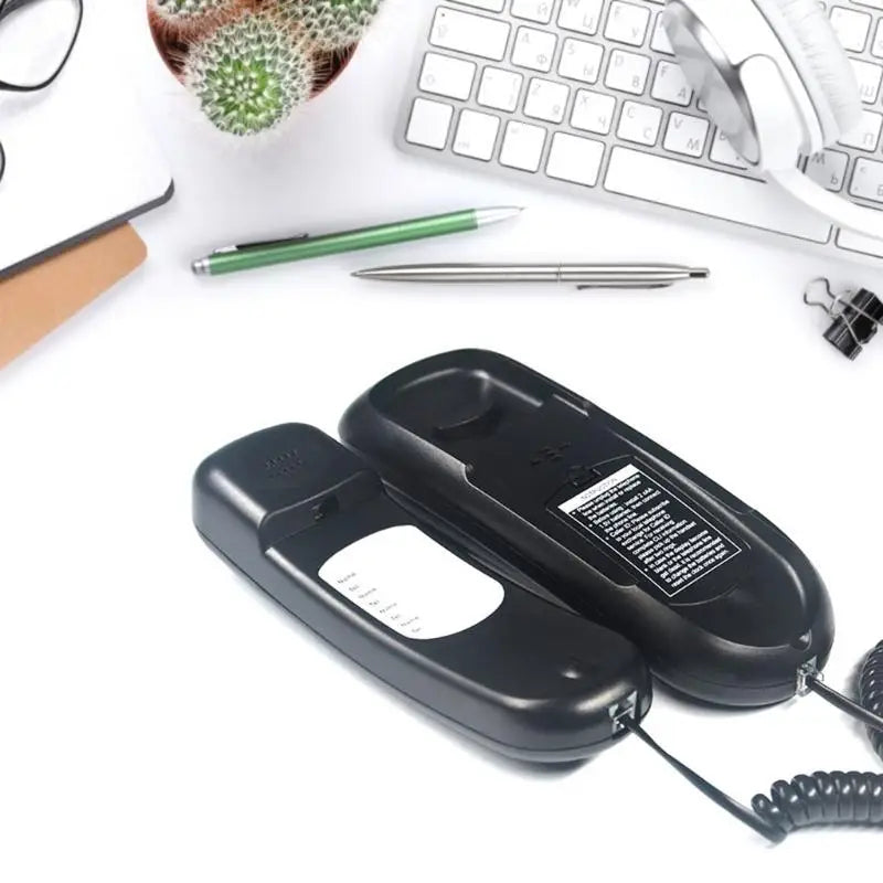 Two black corded telephone handsets with instruction labels and curly cables, displayed on a desk with office items.