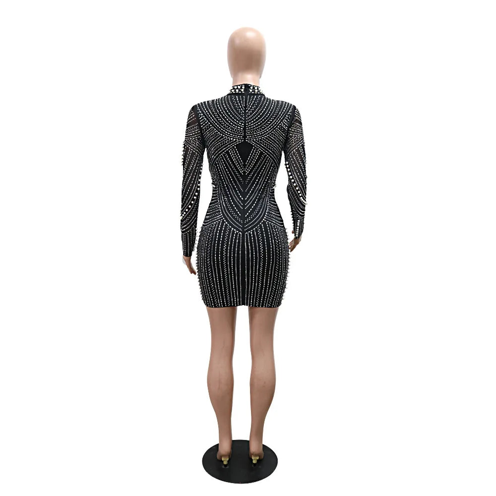 Back view of a black mini dress covered in sparkly rhinestones and pearls, styled with long sleeves.