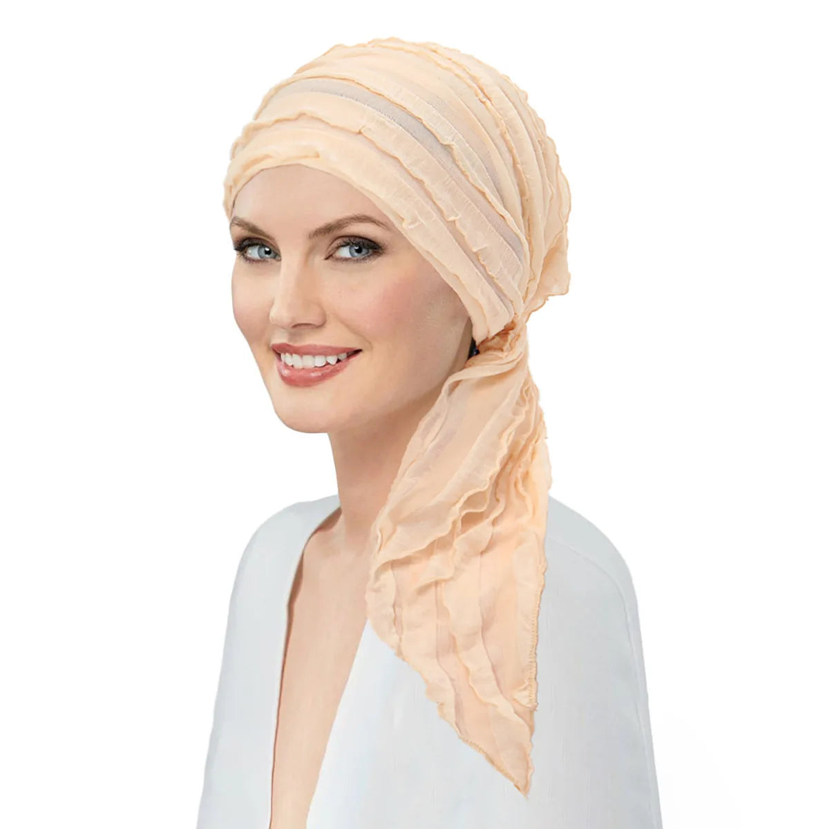 A woman wearing a pale peach, pre-tied elastic turban head wrap with delicate ruffled detailing.
