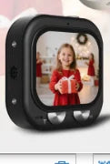 Small black plastic digital photo frame with a screen displaying a girl holding a gift and two silver control knobs.