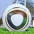 White football with a vibrant, multi-coloured geometric print, resting on green grass.