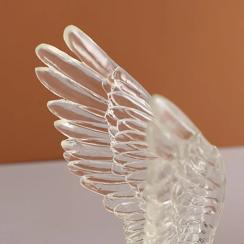 Decorative clear glass angel wings ornament with detailed feathered texture.
