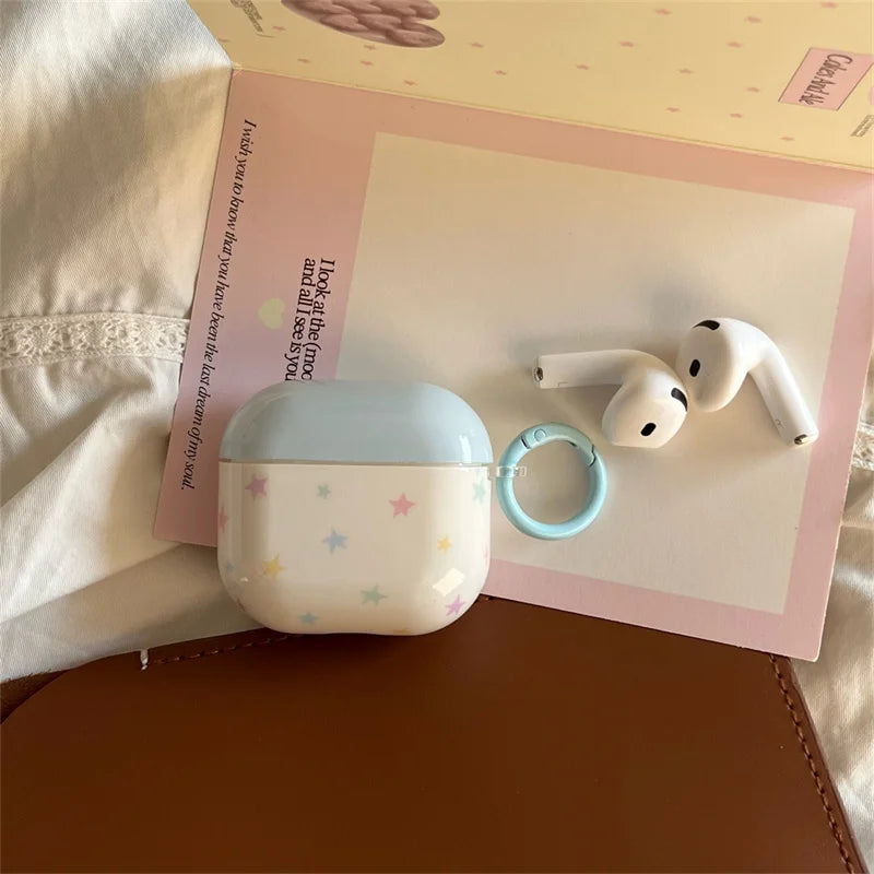 Glossy white AirPods case with a pastel blue lid and star print, featuring a matching blue carabiner ring.