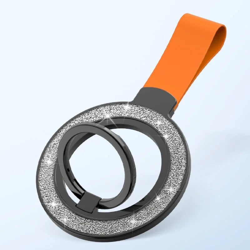 Circular phone ring holder with silver glitter inlay, black frame, and bright orange strap on a light blue background.