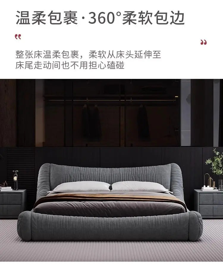 Modern grey upholstered bed frame with a soft, rounded design, textured fabric, and a minimalist style.