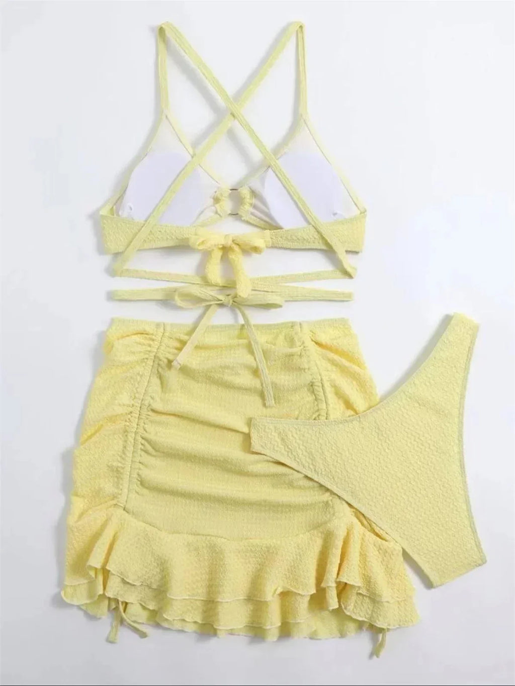 Yellow 3-piece swimsuit with halter top, criss-cross straps, ring link, brief, and ruched ruffle skirt.