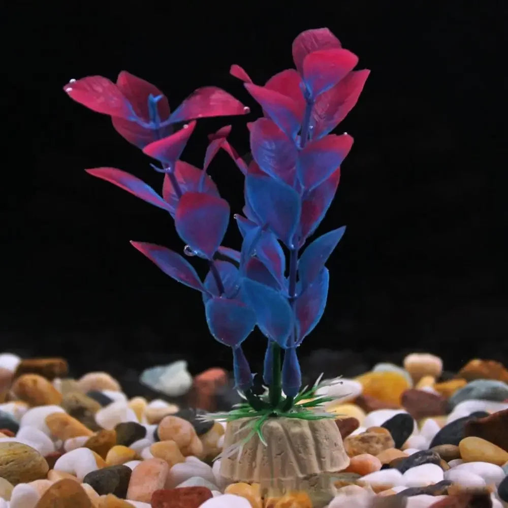 Artificial aquarium plant with blue and pink leaves, anchored in a beige base on multi-colored gravel.
