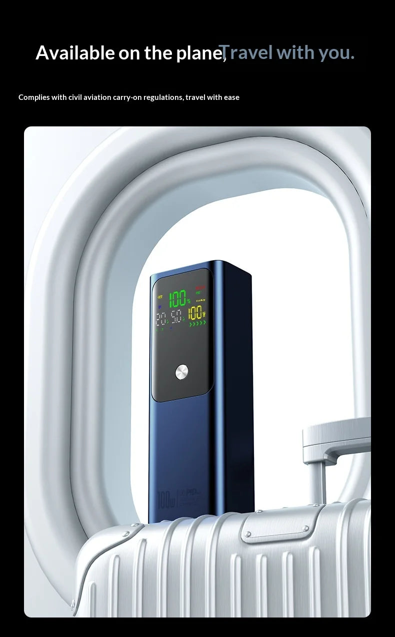 Sleek navy blue 100W laptop power bank with digital display, shown resting on a white suitcase by an aeroplane window.