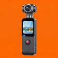 Grey handheld 4K gimbal camera with a touchscreen display showing a mountain landscape, set against an orange background.
