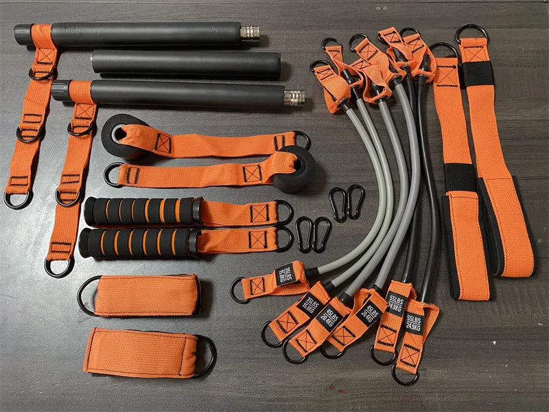 Pilates home fitness kit featuring a black bar, orange straps, resistance bands, handles and metal carabiner clips.