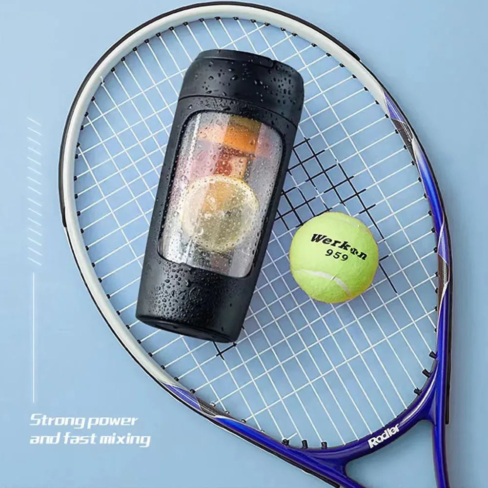 Black portable blender bottle with fruit inside, placed on a tennis racket with a yellow ball. Light blue background.