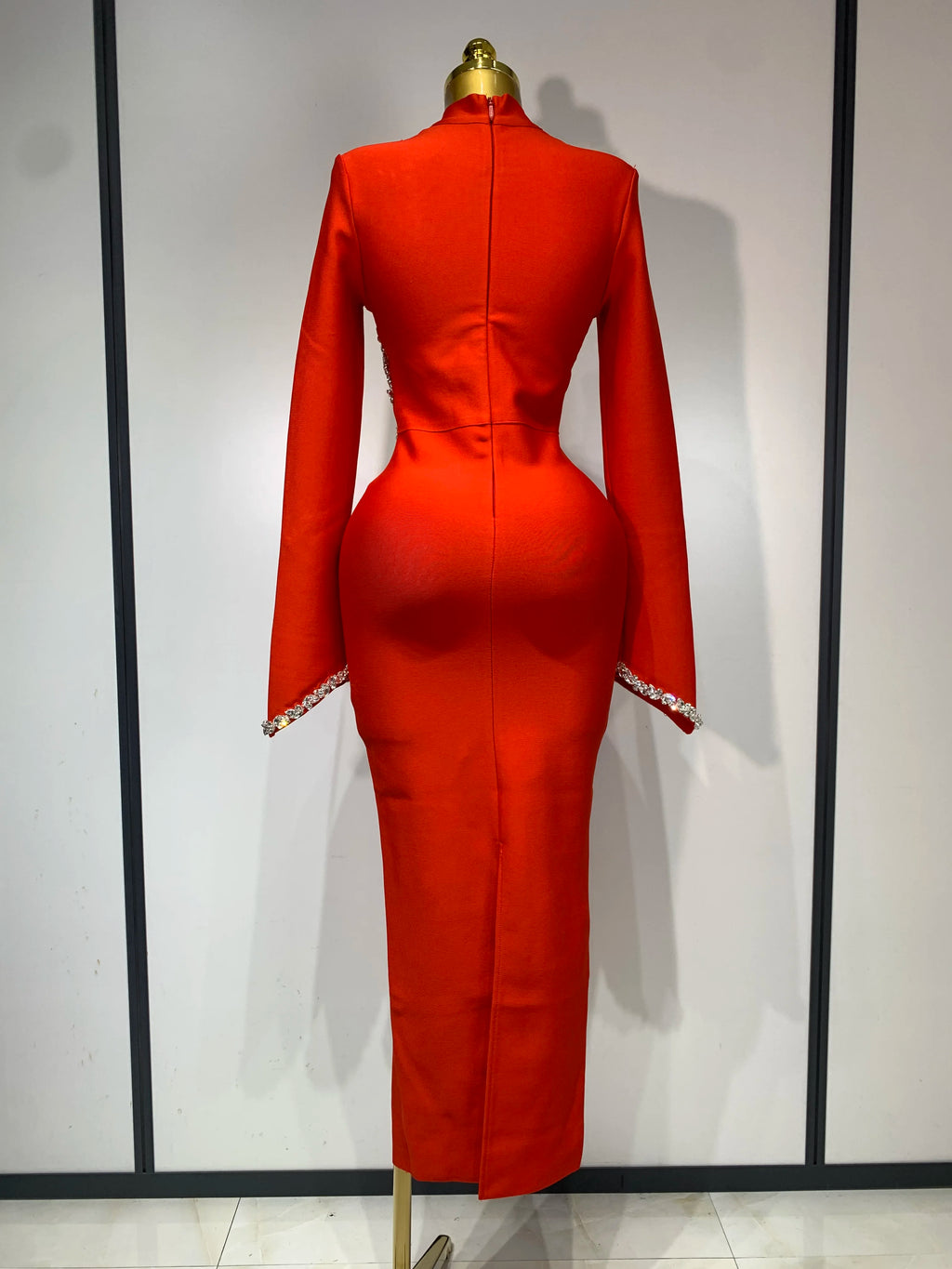 Red long-sleeve bodycon bandage maxi dress on a mannequin, featuring rhinestone cuffs and back zipper.