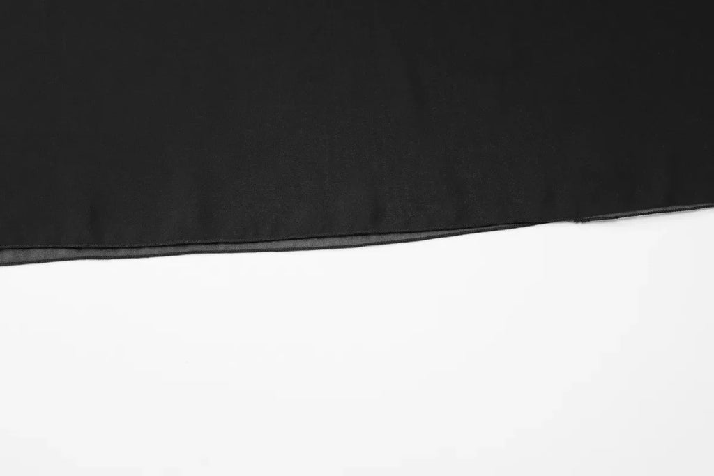 Close-up of smooth, solid black fabric featuring a neat, finished hem edge against a plain white background.