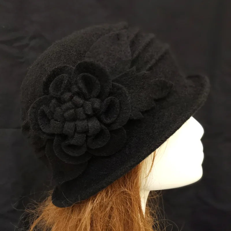 Elegant black wool winter hat with a decorative felt flower detail, shown on a mannequin.