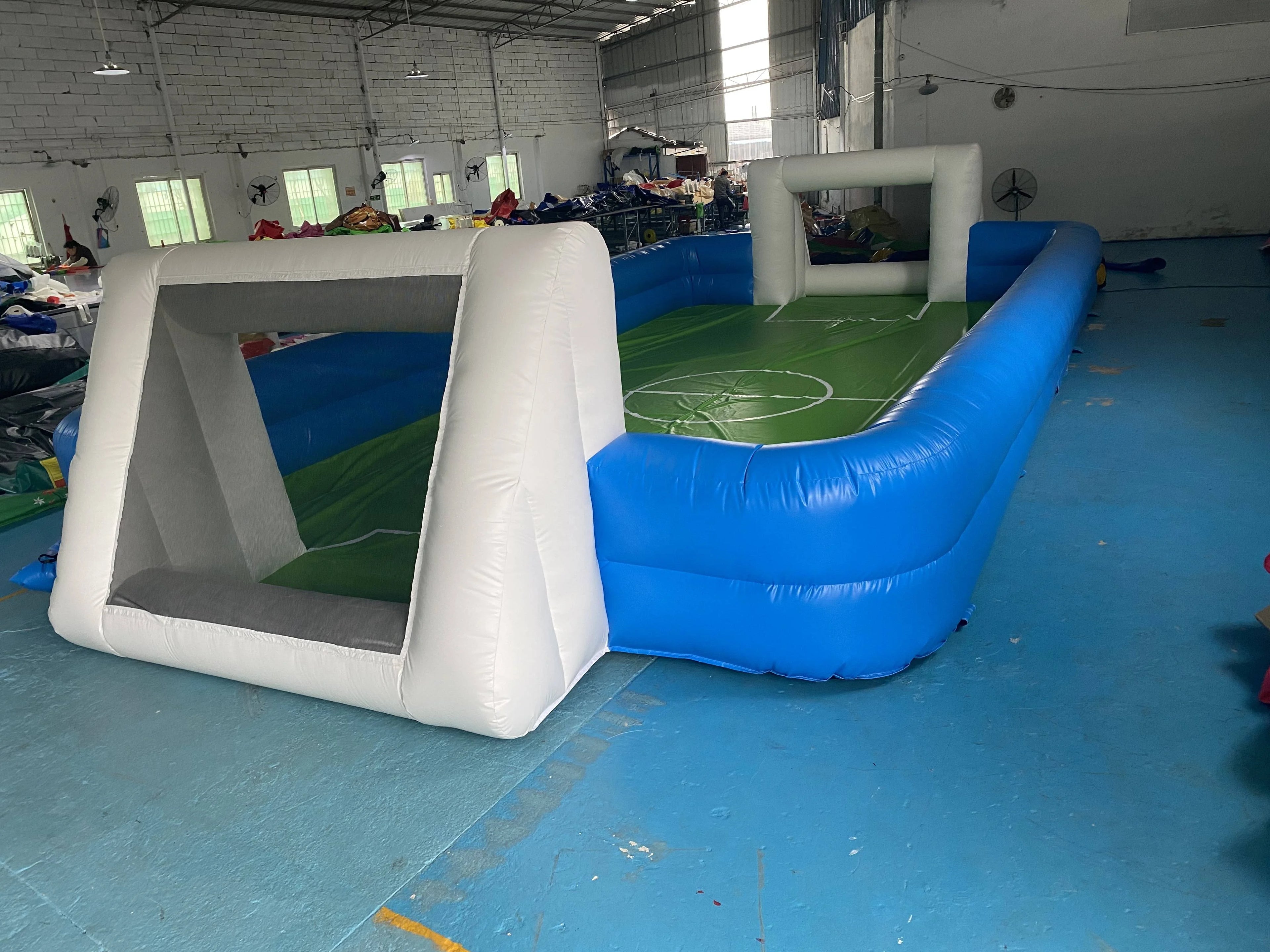 Inflatable football pitch with blue sides and white goals, featuring a green court with white field markings.