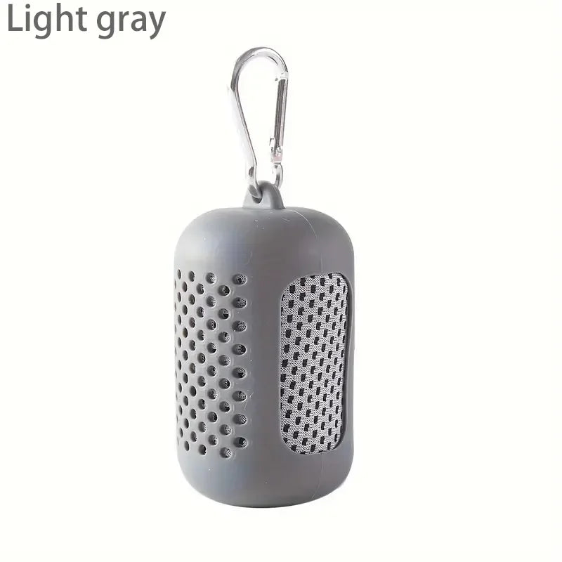 Light grey, perforated silicone carry case with a metal carabiner clip containing a folded grey mesh towel.