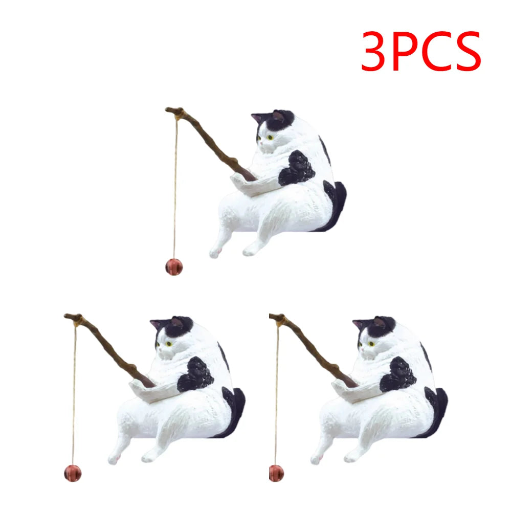 Three black and white cat ornaments, each sitting and holding a fishing rod with a hanging bauble.