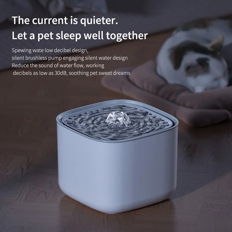 A white, square, minimalist pet water fountain with a bubbling center, set on a floor near a resting cat.