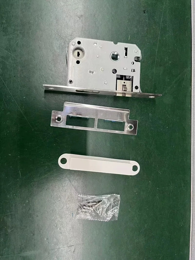 Silver metal door mortise lock set with a strike plate, white plastic cover, and a bag of mounting screws.