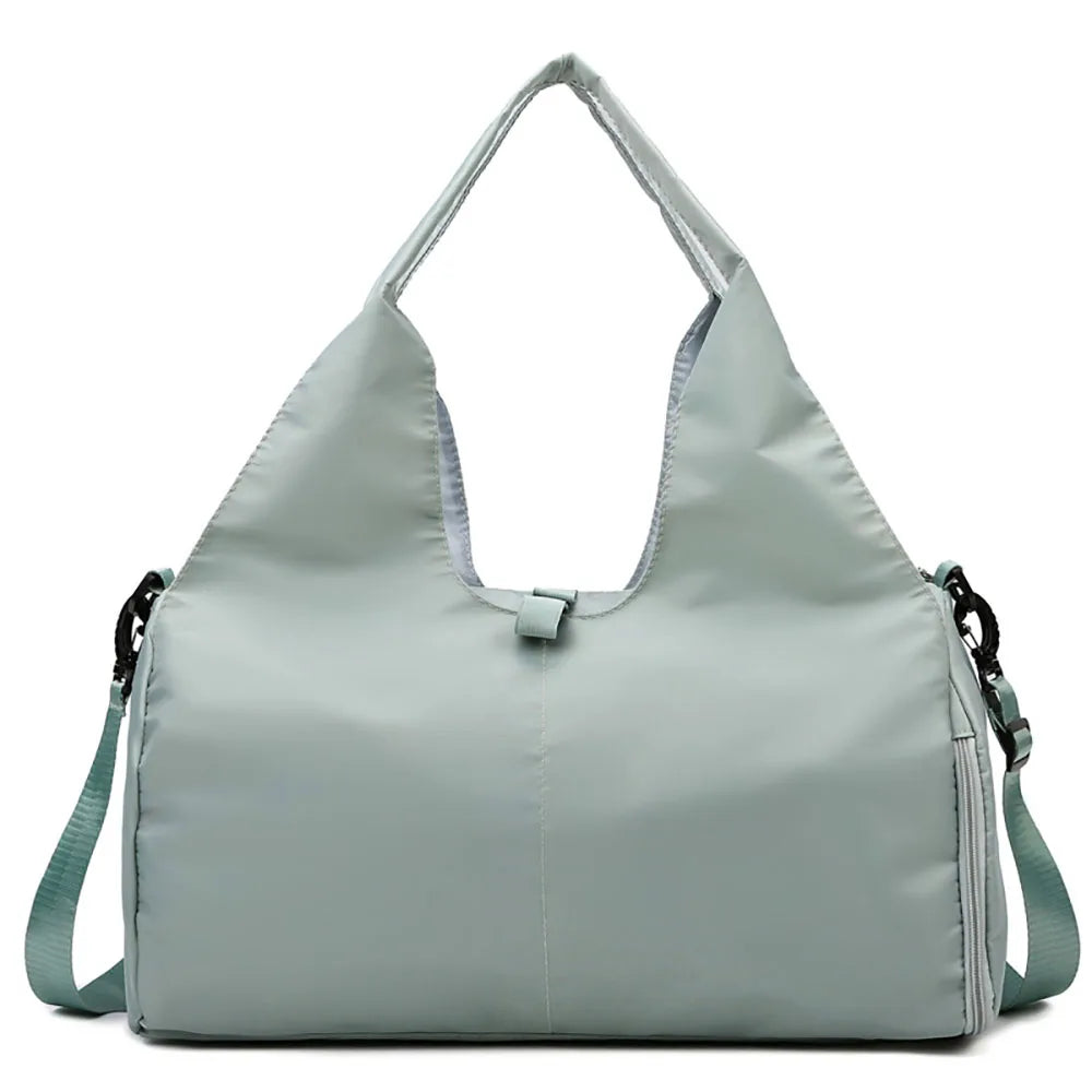 Light sage green duffel bag with dual top handles and an adjustable shoulder strap on a white background.