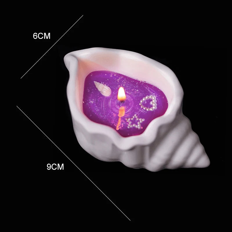 White seashell-shaped candle with purple wax, featuring embedded decorative shell, heart, and star charms. 9x6cm.