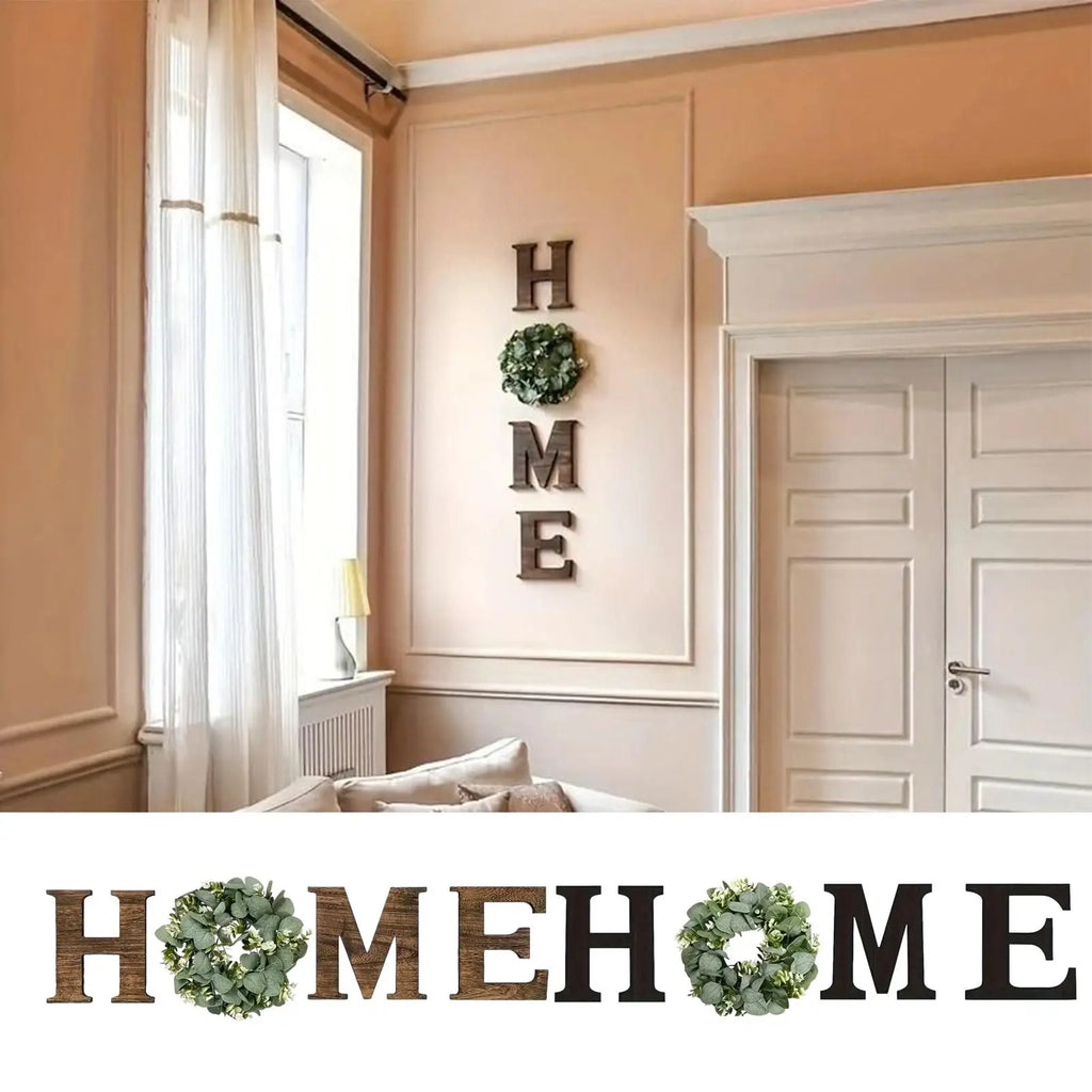 Rustic wooden 'HOME' wall letters with artificial eucalyptus wreaths replacing the letter 'O', displayed in a home.