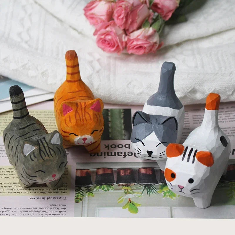 Four hand-carved wooden cat figurines in assorted colours and patterns, featuring minimalist, artistic styling.