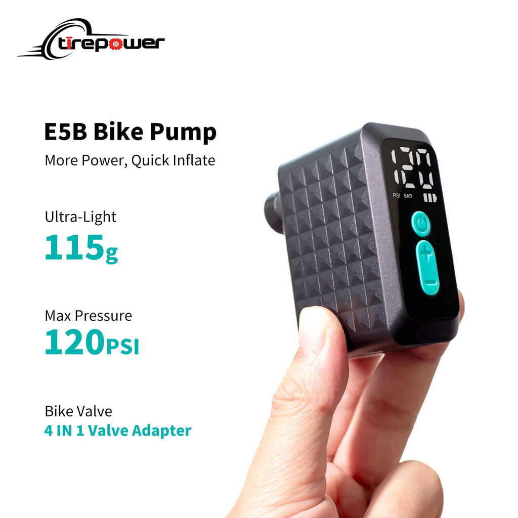 Compact black electric bike pump held in hand, featuring a digital gauge and bright blue control buttons.