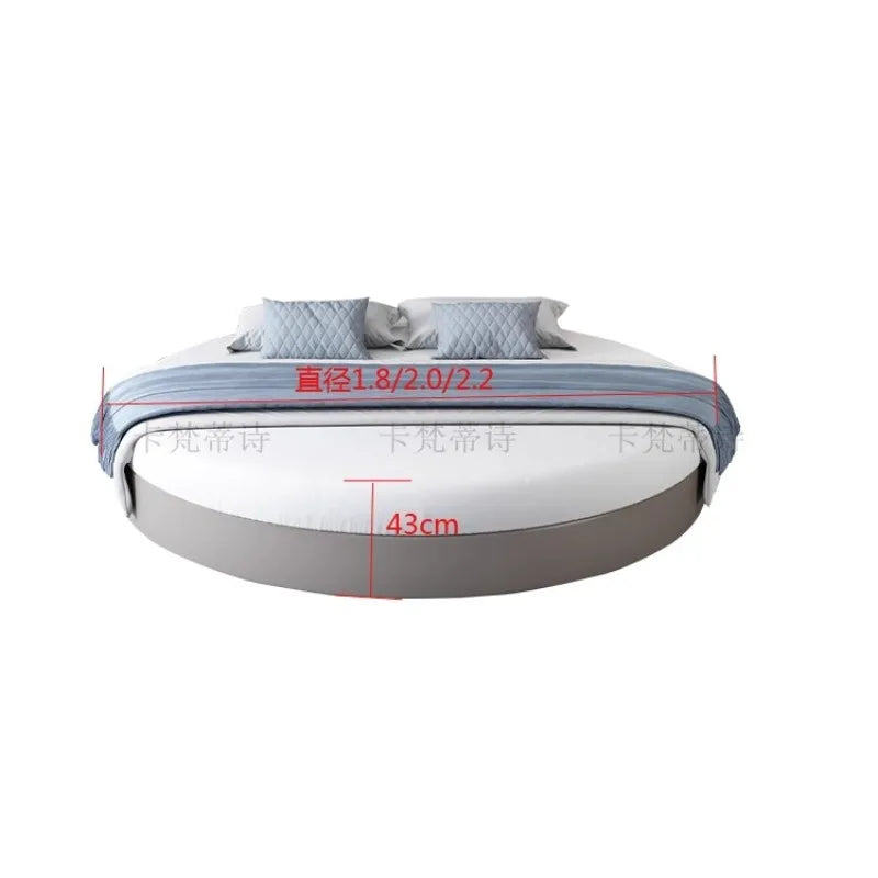 Modern minimalist round double bed frame in a sleek grey finish with white bedding and blue accent cushions.