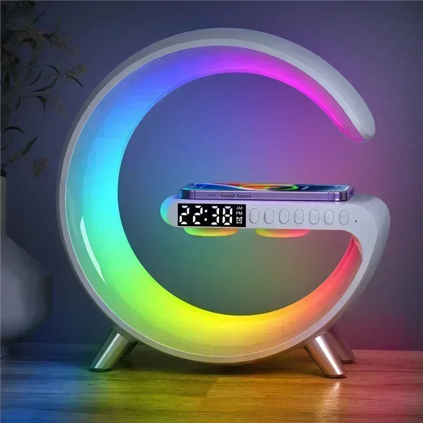 White G-shaped desk lamp featuring a multicoloured LED light, digital alarm clock, and wireless phone charging pad.