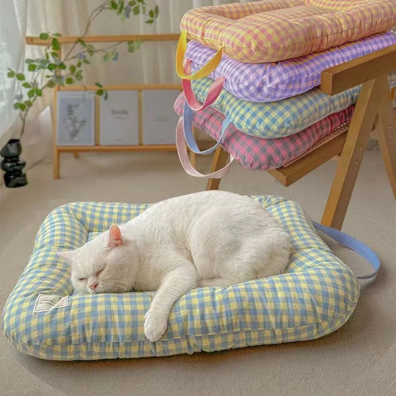 White cat sleeping on a soft, blue and yellow gingham pet mat with raised edges.