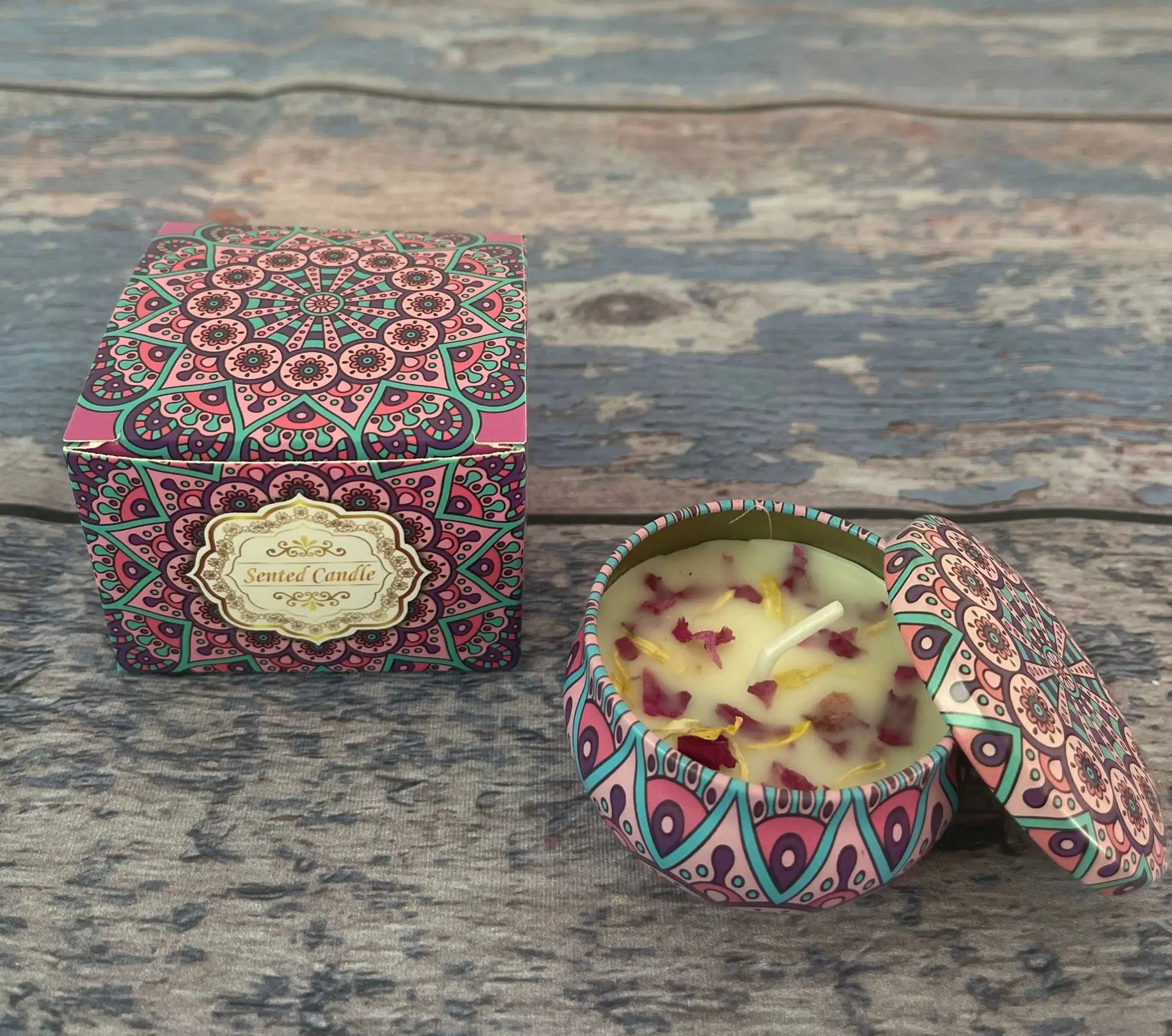 Scented candle in a pink and teal mandala-patterned tin with matching gift box and dried flower petal wax decoration.