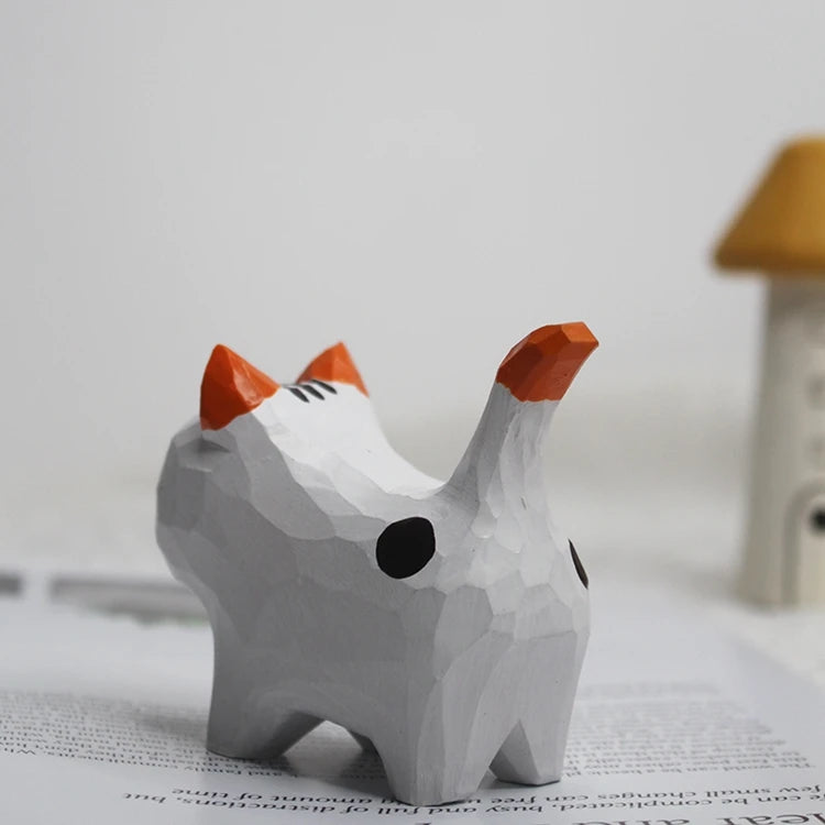 Carved white wooden cat figurine with orange ears, a spotted back, and a tall orange-tipped tail.