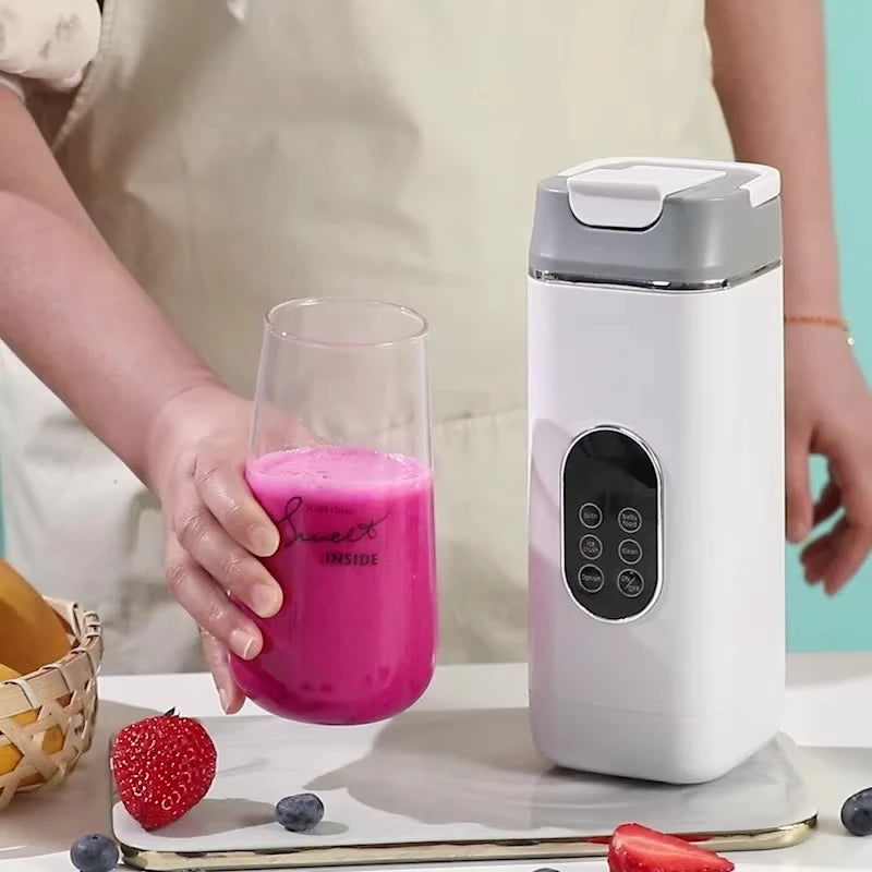 A portable white and grey digital blender next to a glass filled with a pink smoothie, surrounded by fresh fruit.